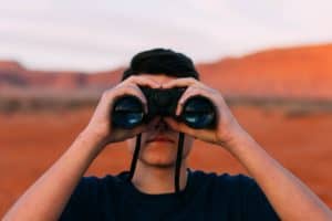 man feeling lost in life and peeking through binoculars