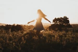 woman wandering through a field feeling joyful