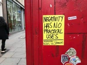 poster on a phone booth that reads: negativity has no practical uses
