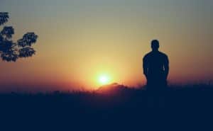 man standing alone looking at the sunrise